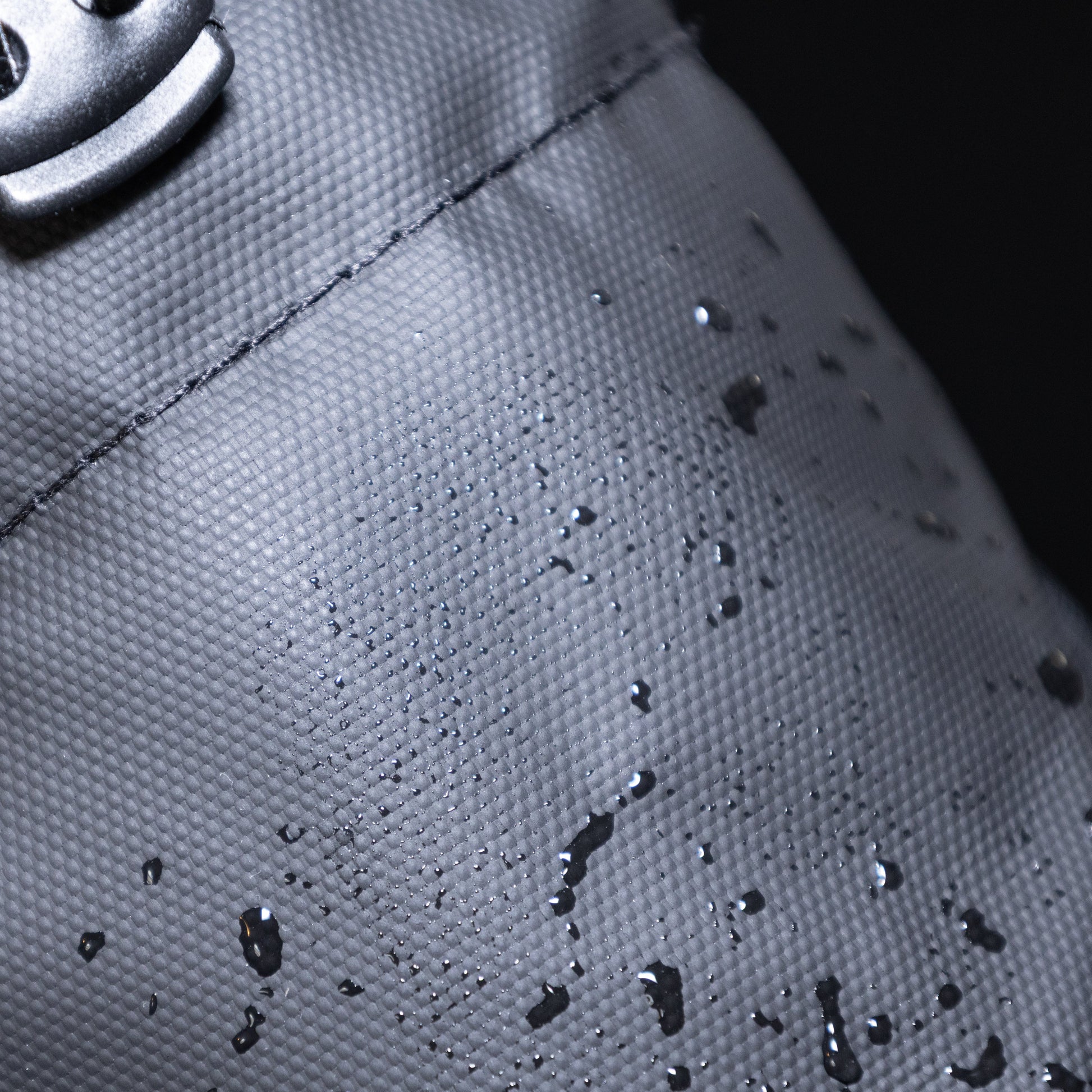 Close-up of a black bag with water droplets, highlighting water resistance.