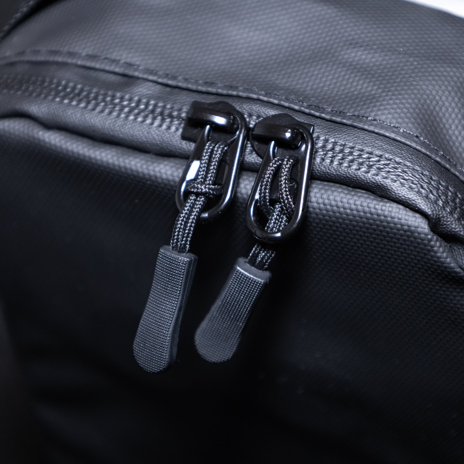 Close-up of a black bag with two zippers on a dark background