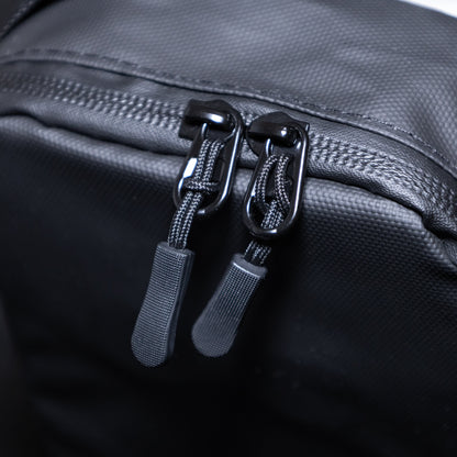 Close-up of a black bag with two zippers on a dark background