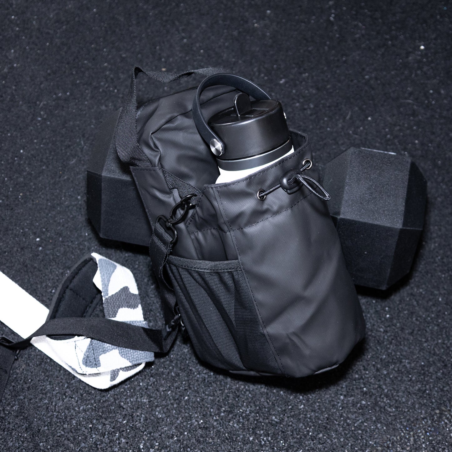 Black hydration pack with water bottle on a dark gym floor